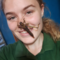 A young woman looks directly into the camera smiling with a large bug on her face