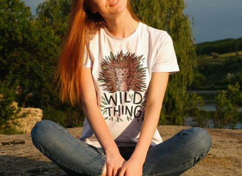 Woman wearing a white tshirt that reads 'Wild Thing' with a hedgehog
