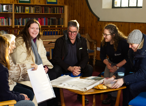 A group of people sit around a table, smiling and chatting